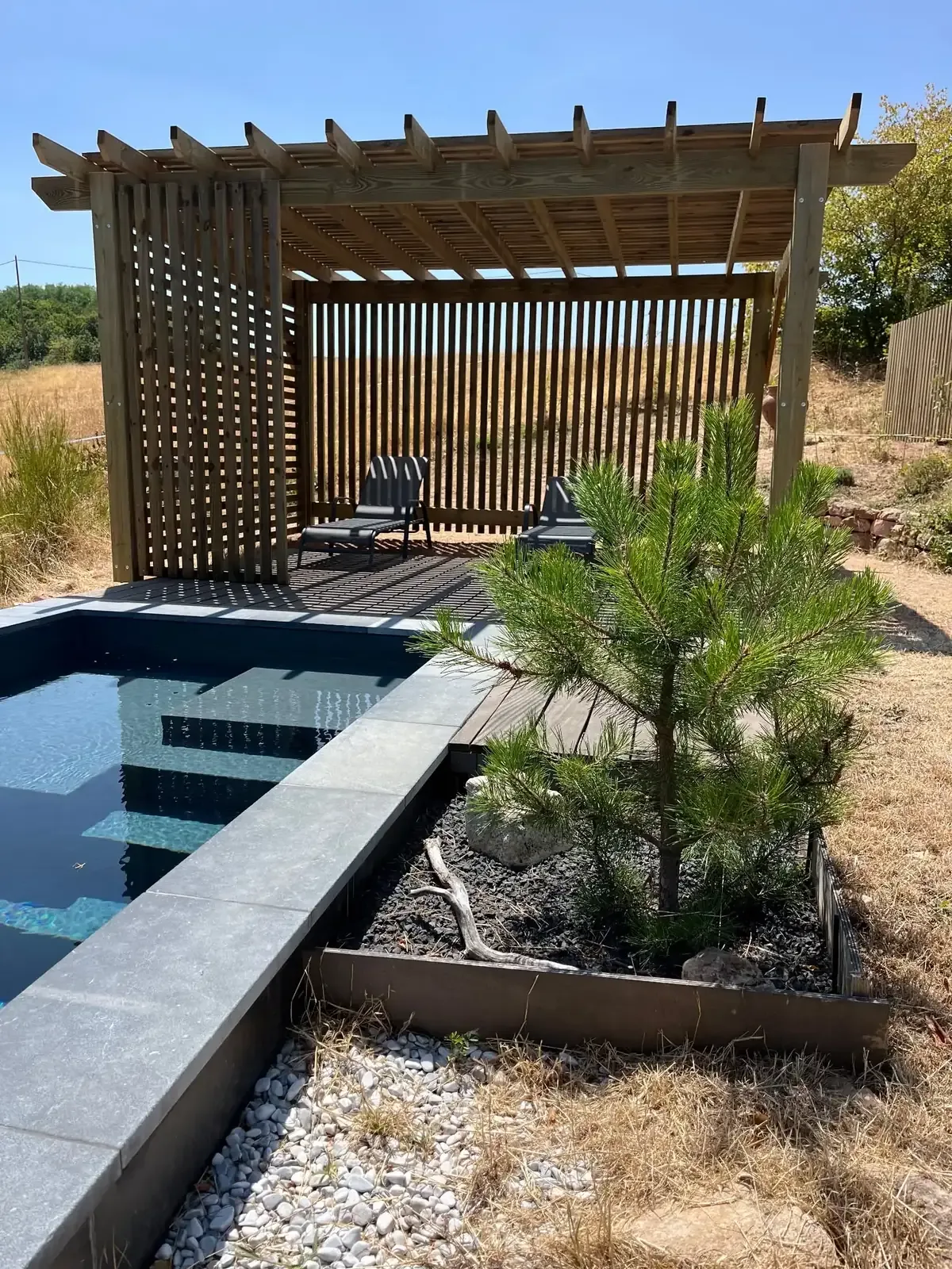 Pergola en bois et piscine avec plage en dalles grises réalisées par ST Création Paysage